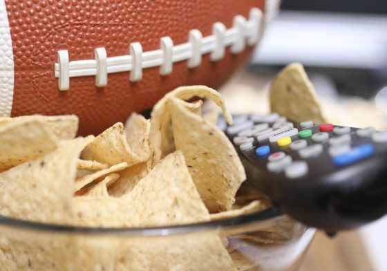 footbal next to a snack bowl and remote control